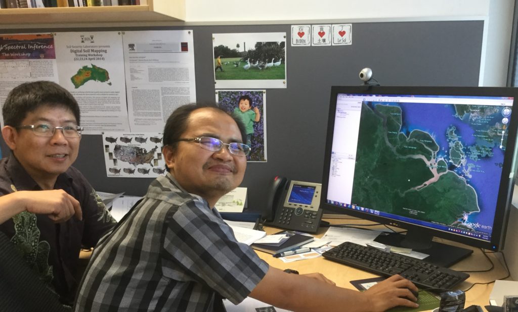 Dr Rudi Yanto (R) and Professor Budiman Minasmy looking at a map of plantations and forest covering some peatlands in Riau, Indonesia